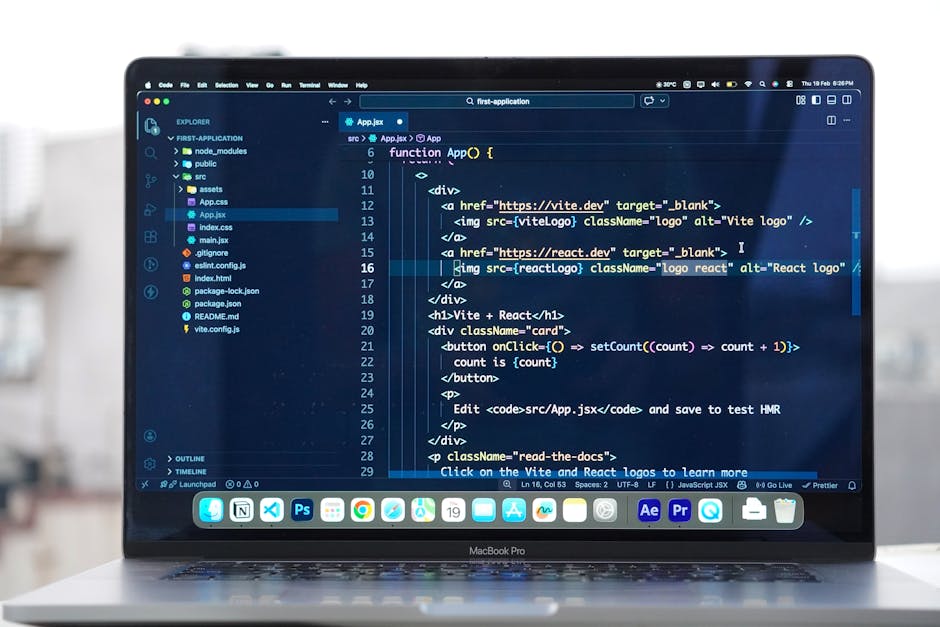 A close-up view of a laptop screen displaying lines of code in a dark-themed editor, with visible HTML and JavaScript elements related to app development. The screen shows code snippets with tags such
